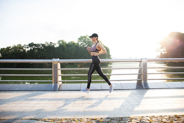 Mujer bonita joven con cuerpo delgado perfecto corriendo al aire libre. Concepto de fitness y funcionamiento.