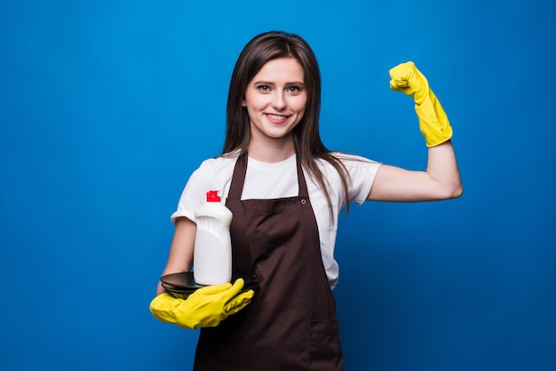 Mujer bonita joven en delantal con platos lavados y jabón para lavar platos. Una botella de jabón para lavar platos con una etiqueta en blanco sobre una pila de platos limpios