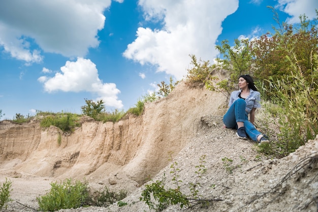 Mujer bonita joven delgada relajarse en la naturaleza con el telón de fondo del desierto, horario de verano