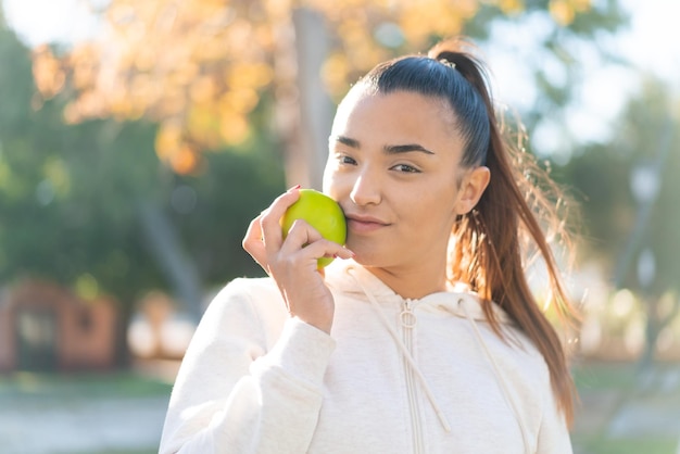 Mujer bonita joven del deporte que sostiene una manzana