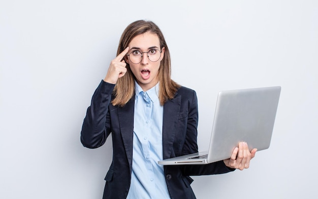 Mujer bonita joven empresaria mirando sorprendido, dándose cuenta de un nuevo pensamiento, idea o concepto. concepto de negocio y portátil