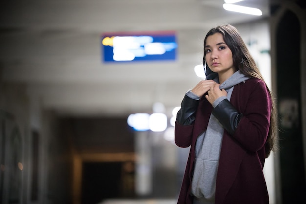 Foto mujer bonita joven esperando el tren en la plataforma del metro noche mirando hacia el lado