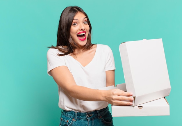 Mujer bonita joven expresión sorprendida y sosteniendo pizzas para llevar y sosteniendo pizzas para llevar