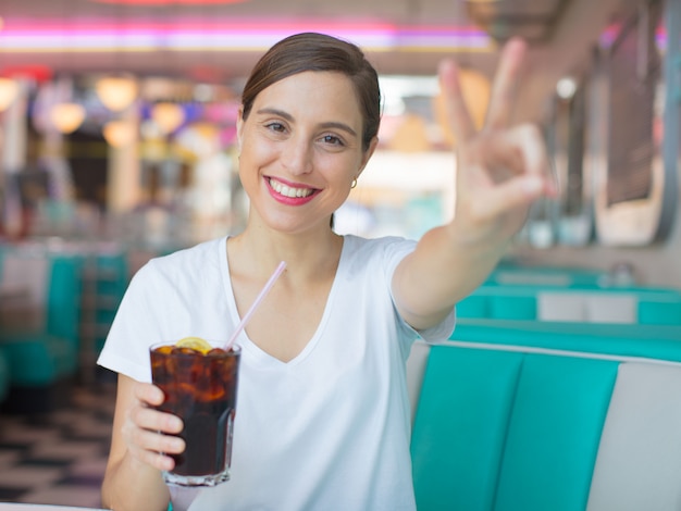 mujer bonita joven feliz y satisfecha bebiendo una cola en un restaurante de cena americano