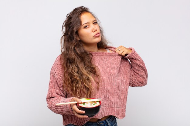 Mujer bonita joven con fideos sintiéndose estresada, ansiosa, cansada y frustrada, tirando del cuello de la camisa, luciendo frustrada con el problema