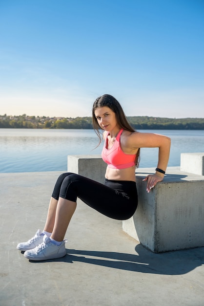 Mujer bonita joven fitness haciendo posturas de yoga, estirando en la naturaleza