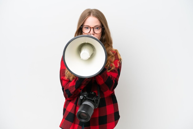 Mujer bonita joven fotógrafo aislado sobre fondo blanco gritando a través de un megáfono