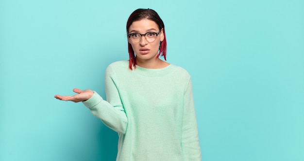 Foto mujer bonita joven gesticulando en la pared de color