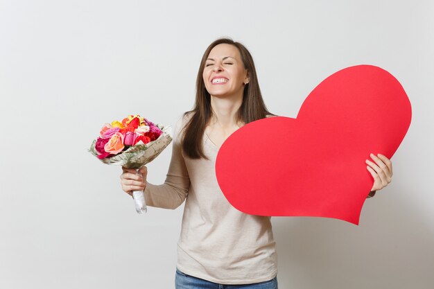 Mujer bonita joven con gran corazón rojo, ramo de flores rosas hermosas sobre fondo blanco. Copie el espacio para publicidad. Lugar para el texto. Concepto del Día de San Valentín o Día Internacional de la Mujer