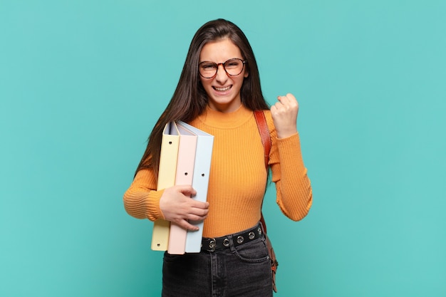 Mujer bonita joven gritando agresivamente con una expresión de enojo o con los puños cerrados celebrando el éxito. concepto de estudiante