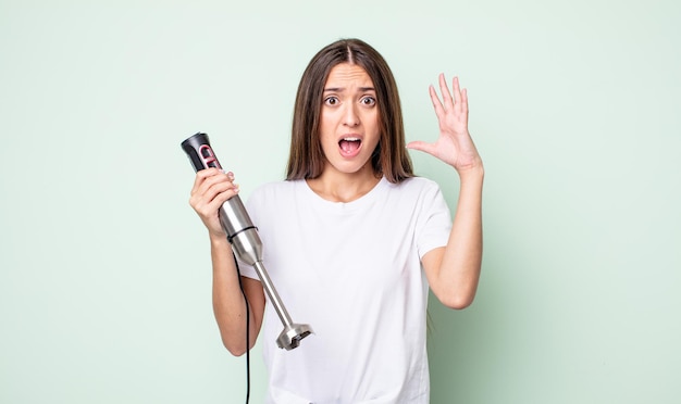 Mujer bonita joven gritando con las manos en el aire. concepto de batidora de mano