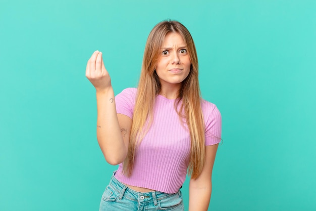 Mujer bonita joven haciendo capice o gesto de dinero, diciéndole que pague