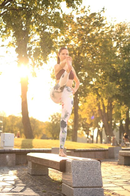 Mujer bonita joven haciendo ejercicios de yoga en el parque.