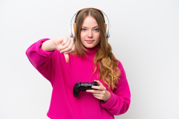 Mujer bonita joven jugando con un controlador de videojuegos aislado sobre fondo blanco mostrando el pulgar hacia abajo con expresión negativa