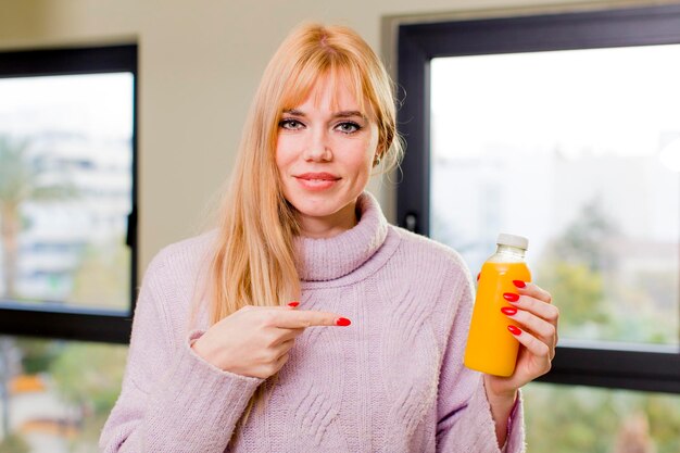 Mujer bonita joven con un jugo de naranja en el interior de su casa