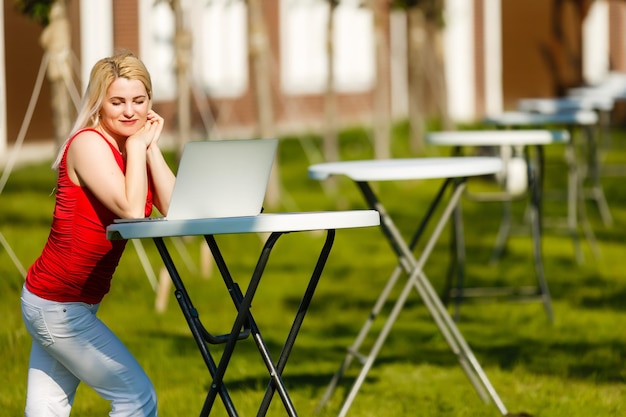 Mujer bonita joven con laptop en el banco en un parque