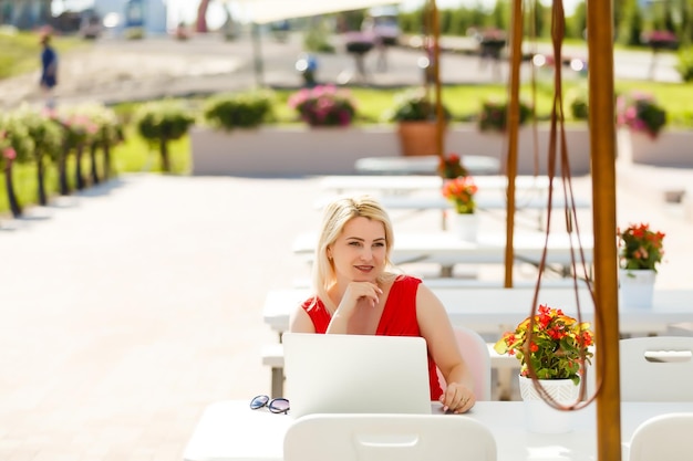 Mujer bonita joven con laptop en el banco en un parque