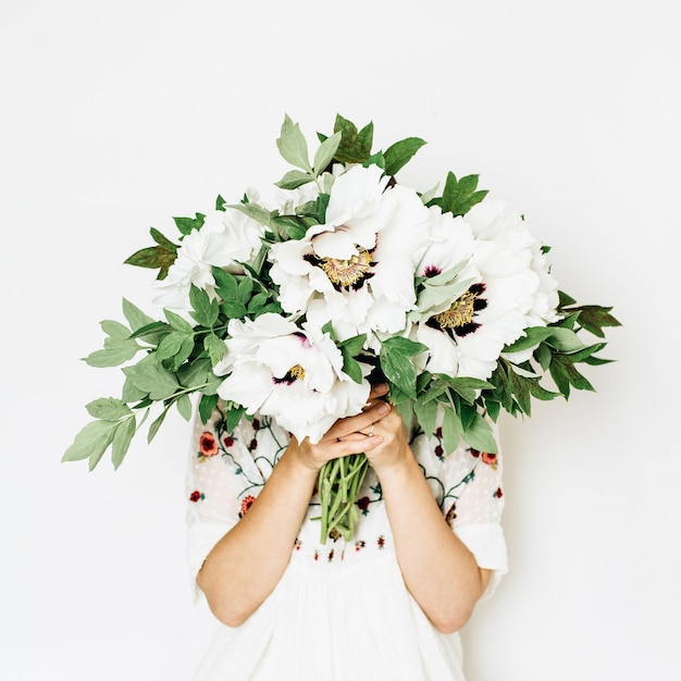 Mujer bonita joven mantenga ramo de flores de peonía blanca sobre superficie blanca