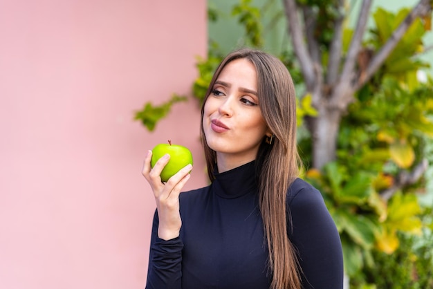 Mujer bonita joven con una manzana al aire libre