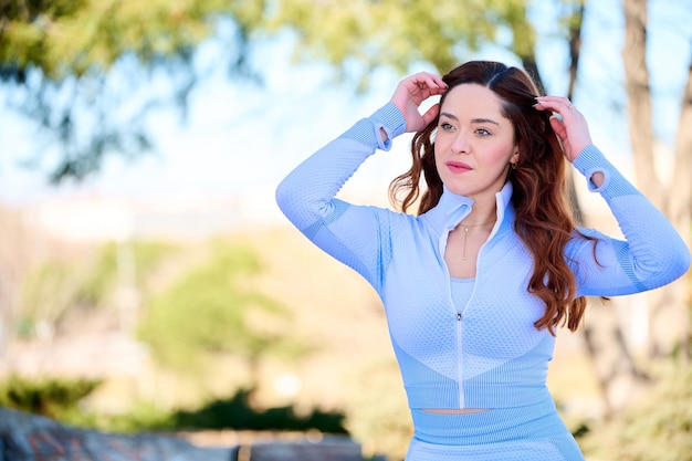 Mujer bonita joven con ojos verdes en vestido azul sentado en el parque de la ciudad