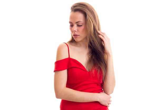 Mujer bonita joven con el pelo largo en vestido rojo diminuto sobre fondo blanco en el estudio