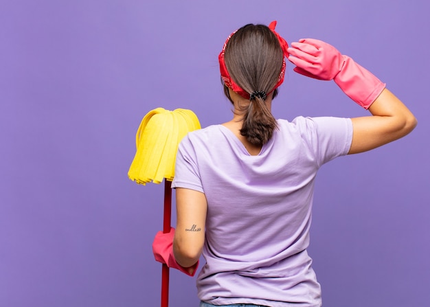 Mujer bonita joven pensando o dudando, rascándose la cabeza, sintiéndose desconcertado y confundido, vista trasera o trasera