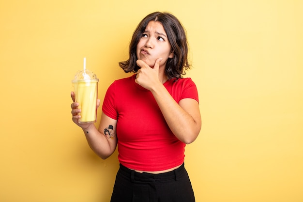 Mujer bonita joven pensando, sintiéndose dudoso y confundido. concepto de batido