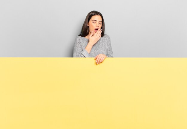 Mujer bonita joven que bosteza perezosamente temprano en la mañana, se despierta y se ve somnolienta, cansada y aburrida. copia espacio para colocar tu concepto