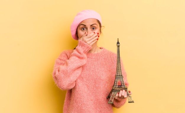 Mujer bonita joven que cubre la boca con las manos con un concepto de París conmocionado