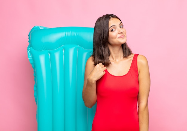 Mujer bonita joven que parece arrogante, exitosa, positiva y orgullosa, apuntando a sí misma