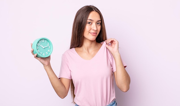 Mujer bonita joven que parece arrogante, exitosa, positiva y orgullosa. concepto de reloj despertador