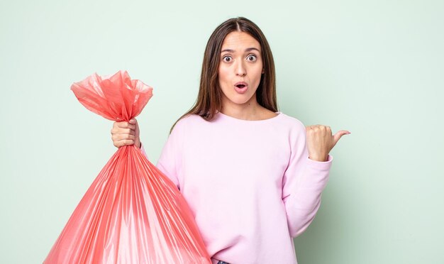 Mujer bonita joven que parece asombrada por el concepto de basura de incredulidad