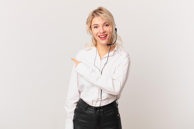 Mujer bonita joven que parece emocionada y sorprendida apuntando hacia el lado. concepto de telemarketing