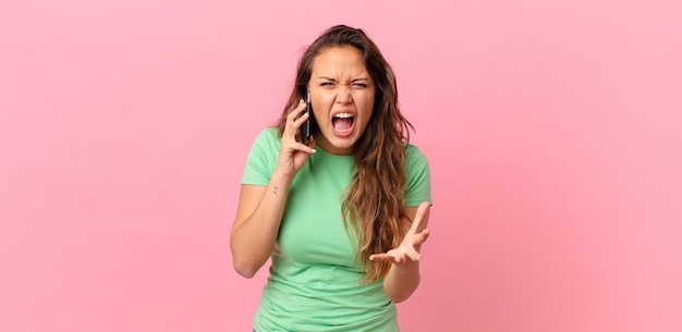 Mujer bonita joven que parece enojada, molesta y frustrada y que sostiene un teléfono inteligente