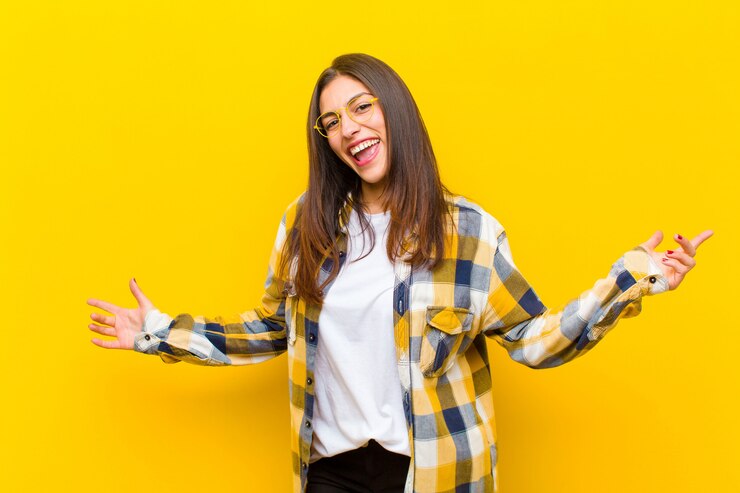 Foto mujer bonita joven que parece feliz, arrogante, orgullosa y satisfecha de sí misma, sintiéndose como la número uno contra la pared naranja