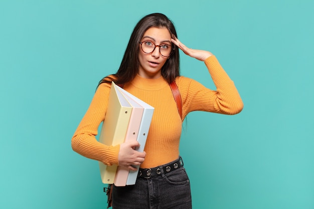 Mujer bonita joven que parece feliz, asombrada y sorprendida, sonriendo y dándose cuenta de buenas noticias asombrosas e increíbles. concepto de estudiante