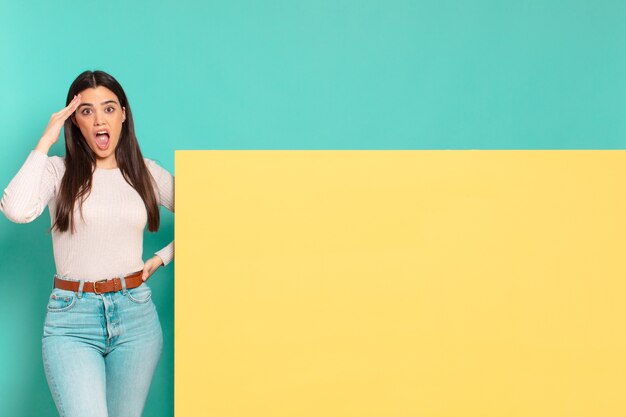 Mujer bonita joven que parece feliz, asombrada y sorprendida, sonriendo y dándose cuenta de buenas noticias asombrosas e increíbles. copia espacio para colocar tu concepto