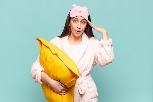 Mujer bonita joven que parece feliz, asombrada y sorprendida, sonriendo y dándose cuenta de buenas noticias asombrosas e increíbles. despertar vistiendo concepto de pijama