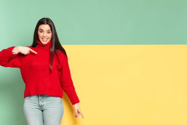 Mujer bonita joven que parece feliz, orgullosa y sorprendida, apuntando alegremente a sí misma, sintiéndose segura y elevada. copia espacio para colocar tu concepto