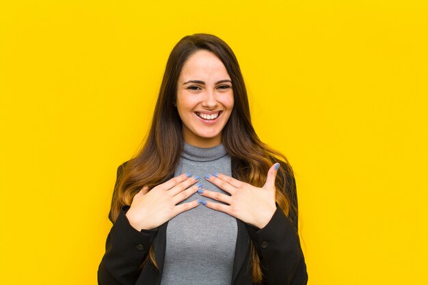 Foto mujer bonita joven que parece feliz, sorprendida, orgullosa y emocionada, apuntando al concepto de autoempleo o negocio