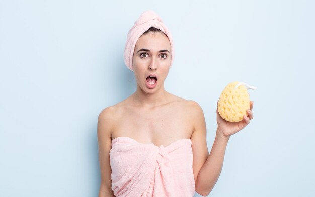 Mujer bonita joven que parece muy consternada o sorprendida. concepto de ducha y esponja