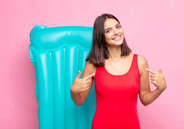 Mujer bonita joven que parece orgullosa, arrogante, feliz, sorprendida y satisfecha, apuntando a sí misma, sintiéndose como una ganadora