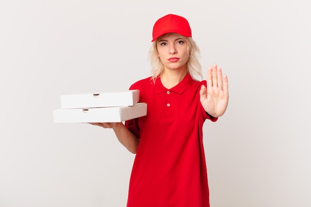 Mujer bonita joven que parece seria que muestra la palma abierta que hace el gesto de la parada. concepto de entrega de pizza