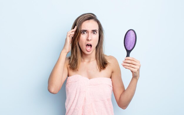 Mujer bonita joven que parece sorprendida, dándose cuenta de un nuevo pensamiento, idea o concepto. concepto de cepillo para el cabello