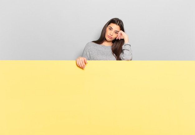 Mujer bonita joven que se siente aburrida, frustrada y con sueño después de una tarea aburrida, aburrida y tediosa, sosteniendo la cara con la mano. copia espacio para colocar tu concepto