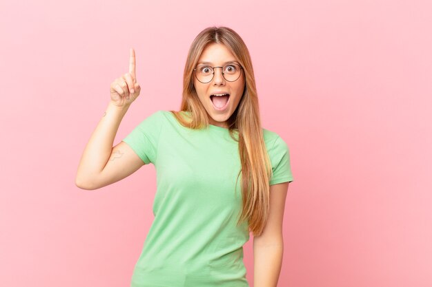 Mujer bonita joven que se siente como un genio feliz y emocionado después de darse cuenta de una idea