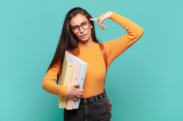 Mujer bonita joven que se siente confundida y desconcertada, mostrando que estás loco, loco o loco. concepto de estudiante