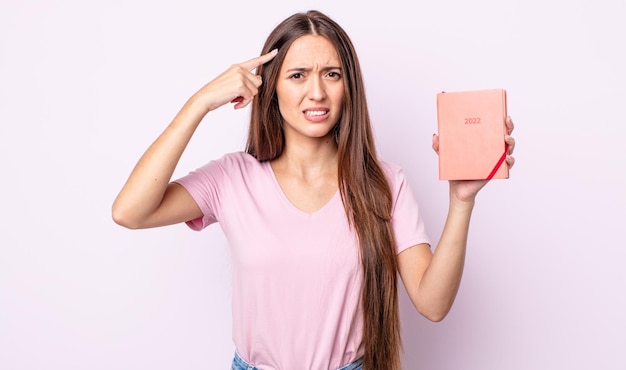 Mujer bonita joven que se siente confundida y perpleja, mostrando que estás loco. Concepto de planificador 2022