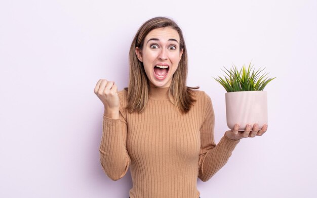 Mujer bonita joven que se siente conmocionada, riendo y celebrando el éxito. concepto de planta