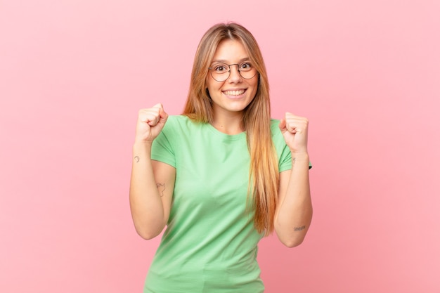 Mujer bonita joven que se siente conmocionada, riendo y celebrando el éxito